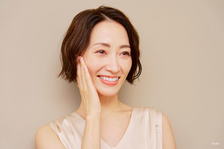 Asian woman with short hair touching her face
