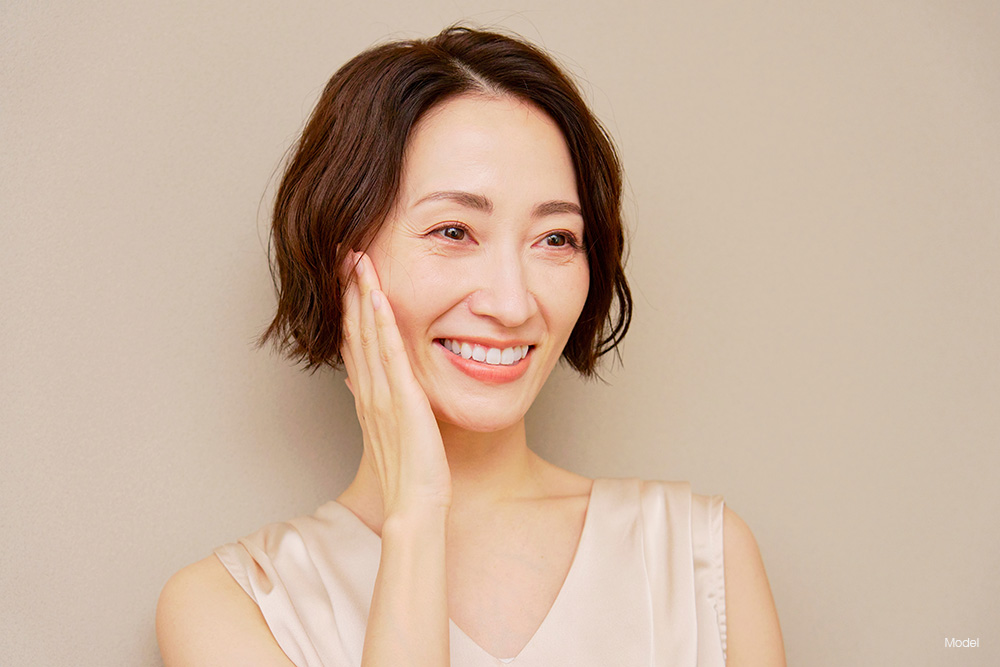 Asian woman with short hair touching her face