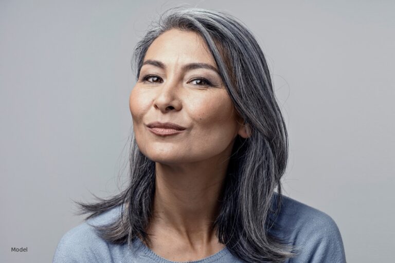 Mature Asian woman with salt-and-pepper hair, light gray background